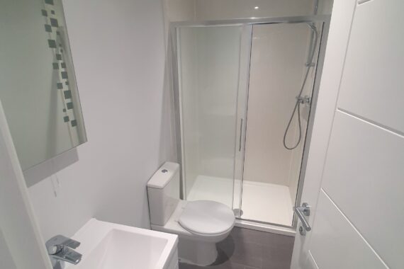 White and silver bathroom with stone tile flooring installed by Top Drawer Construction Woking Weybridge Surrey